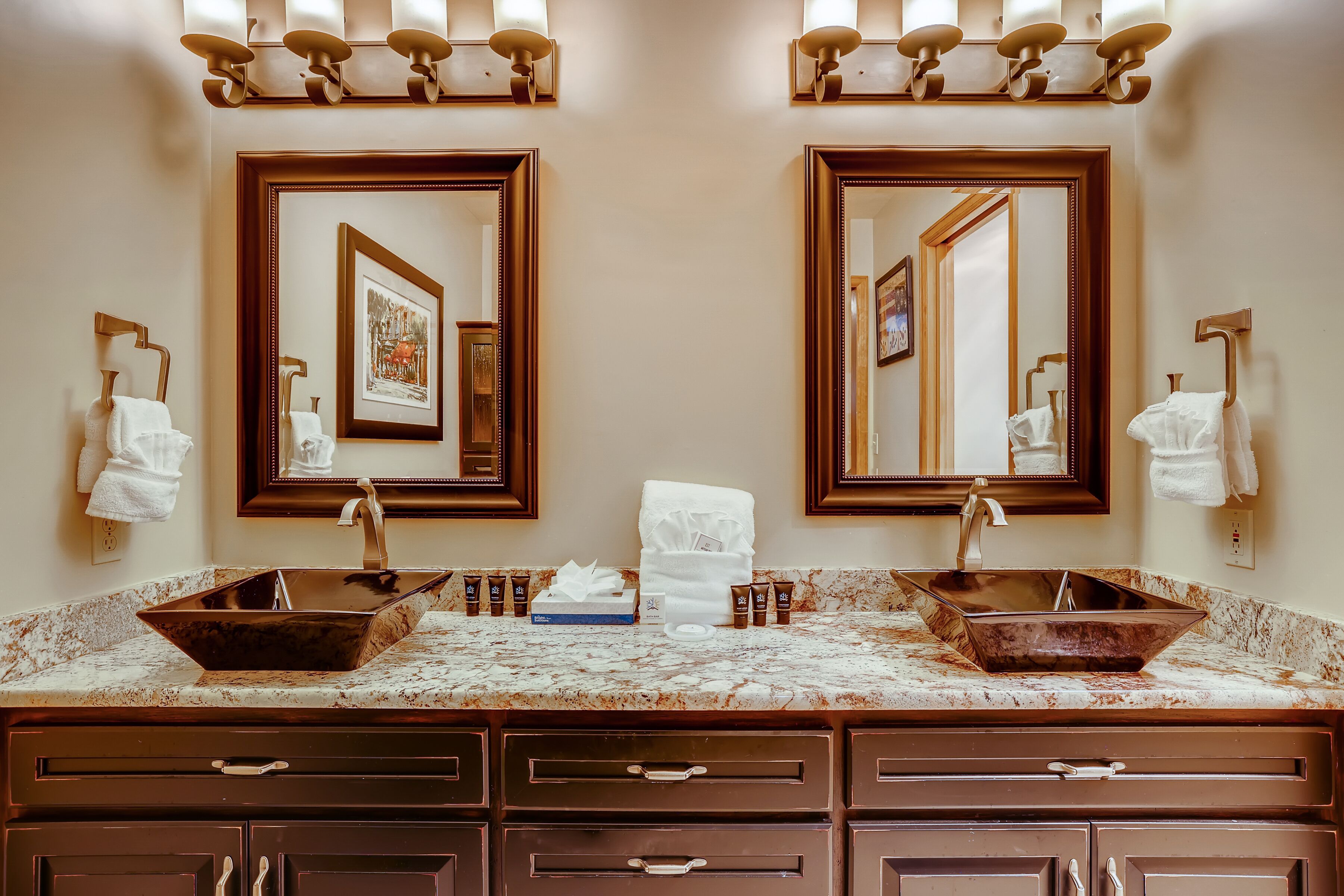 A bathroom with two sinks, marble countertops, and wooden cabinets.