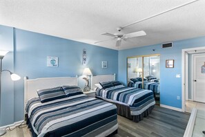 A room with two beds, a ceiling fan, and a mirror.