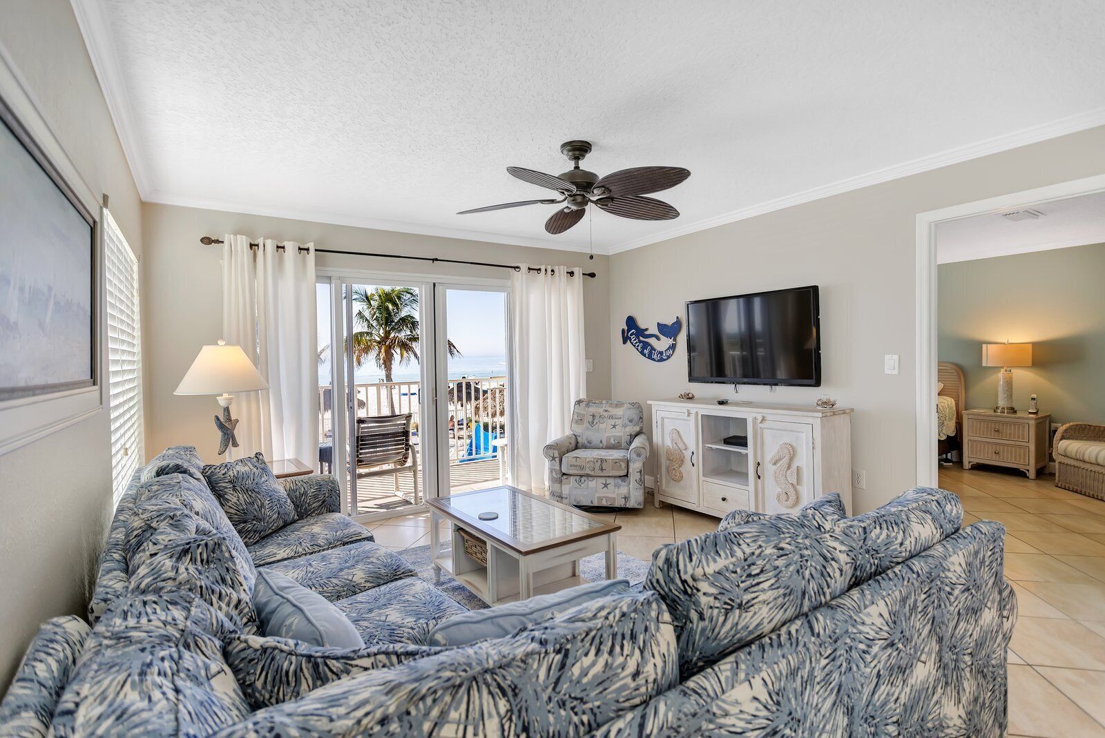 A living room with a sofa set, a TV, and a ceiling fan.