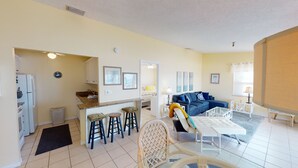 A compact living space with a kitchenette, a dining area, and a seating area with a sofa and chairs. - Beach Front 1B1B Balcony 2 Beds - Surf Song #349 (Madeira Beach)
