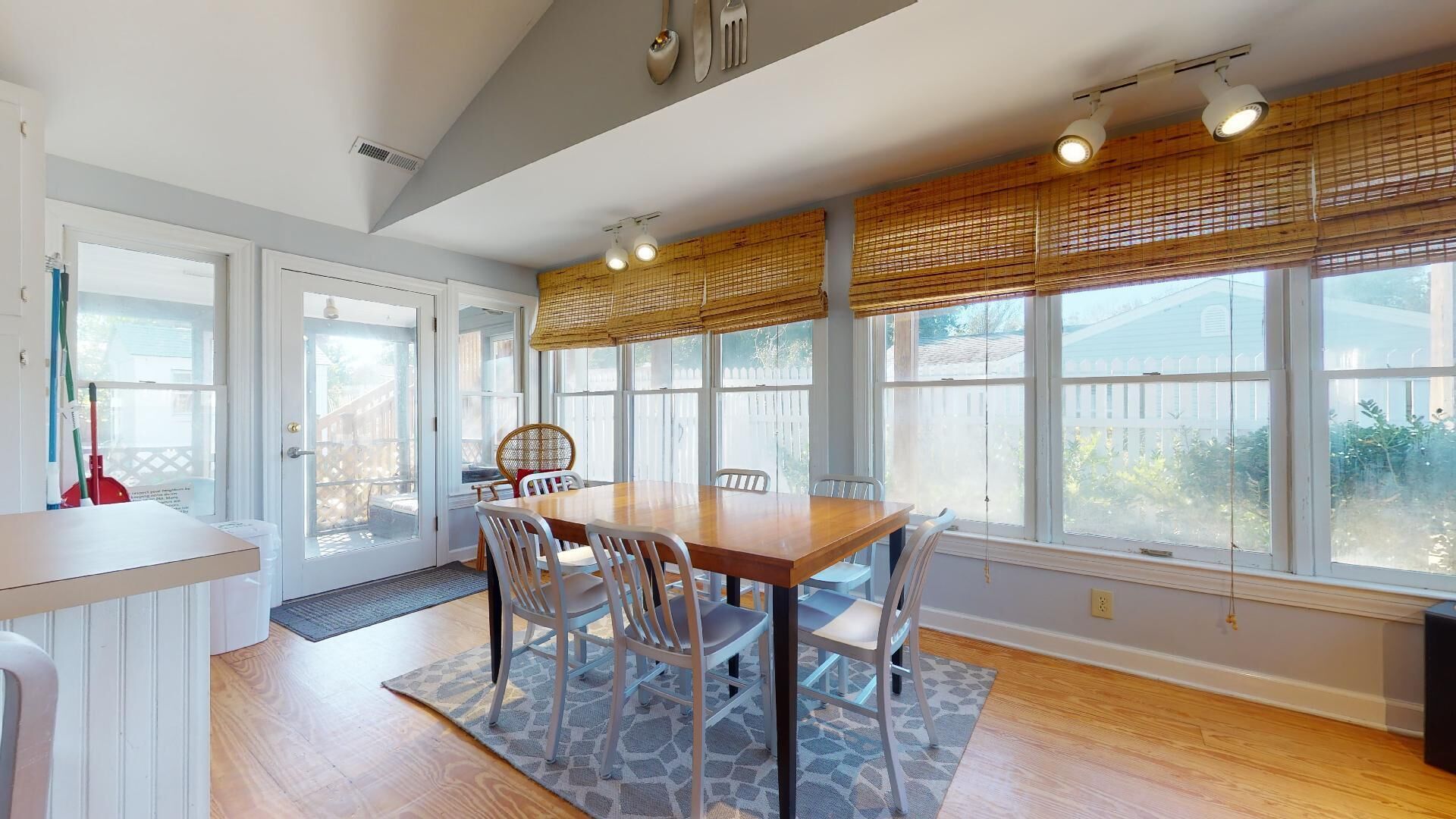 A bright kitchen with a dining table, chairs, and large windows.