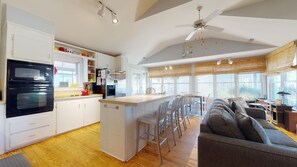 A modern kitchen with a central island, white cabinetry, and a black oven. - Dog friendly beach home with fence,screened porch,sun deck,charcoal grill (Isle of Palms)