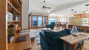 A spacious living area with a large sofa, wooden coffee table, and a view of the ocean through the sliding glass doors. - Russell's Rendezvous - Enjoy a Vacation Full of Adventure! (Dresden)