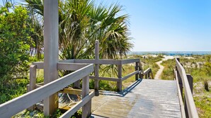 A wooden boardwalk leading to a beach with palm trees and a clear sky. - Gorgeous dual-level ocean view unit located in Wild Dunes (Isle of Palms)