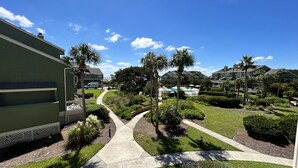 A residential area with a pathway, green lawns, and houses with a pool. - Gorgeous dual-level ocean view unit located in Wild Dunes (Isle of Palms)