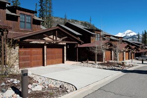 A row of wooden cabins with stone foundations, set against a backdrop of a snow-capped mountain and clear blue sky. - Largest Black Bear Townhome - Ping Pong Table - on Demand Ski Shuttle (Durango)