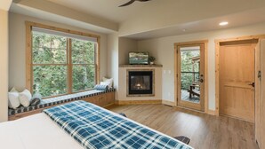 A spacious room with a large window, a fireplace, a ceiling fan, and a door leading to an outdoor deck. - Largest Black Bear Townhome - Ping Pong Table - on Demand Ski Shuttle (Durango)