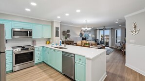 A modern kitchen with stainless steel appliances, teal cabinetry, and a central island. - Beautiful oceanfront condo overlooking the pool and beach in Wild Dunes (Isle of Palms)