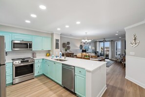Una cocina moderna con electrodomésticos de acero inoxidable, armarios color turquesa y una isla central.