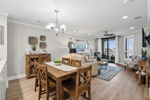 Una sala de estar moderna con comedor, muebles de madera y decoración mural.