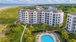A multi-story hotel with a pool, surrounded by greenery and a view of the beach. - Beautiful oceanfront condo overlooking the pool and beach in Wild Dunes (Isle of Palms)