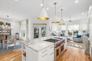 A modern kitchen with a central island, white cabinetry, and stainless steel appliances. - Beautifully decorated home in Wild Dunes with beach access and rooftop deck (Isle of Palms)