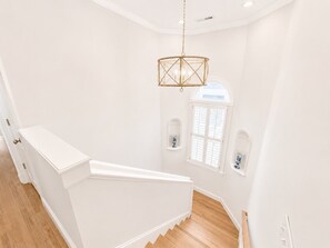 Un escalier avec une rampe blanche et des marches en bois menant à un palier.