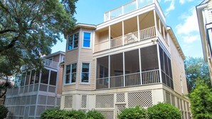 Une maison à deux étages avec un balcon au deuxième étage, une véranda dotée de balustrades en treillis et une véranda grillagée au premier étage.