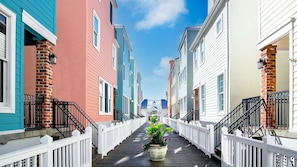 A narrow wooden walkway flanked by colorful buildings with white railings and black railings on the stairs.