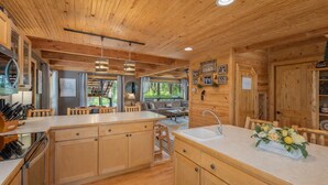A wooden cabin interior with a kitchen, dining area, and a cozy living space. - Thyme Out/ HotTub, WIFI, Fenced Dog Space, Forest (Leavenworth)