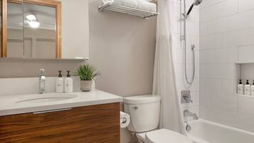 Un baño con lavamanos, inodoro, ducha y espejo.