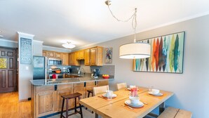 Una cocina moderna con armarios de madera, encimera de granito y comedor con mesa y sillas de madera.