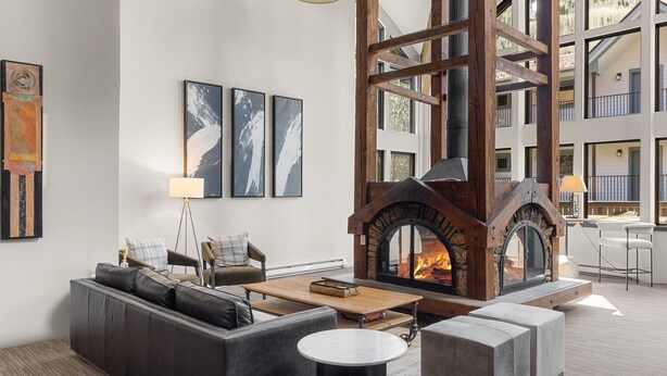Una sala moderna con chimenea de piedra, sofá de cuero y obras de arte en la pared.