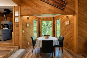 A wooden interior with a dining table, chairs, and a view through large windows. - On Fish Lake | Views | Private Dock | Deck | BBQ (Leavenworth)