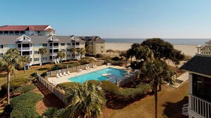 A hotel with a swimming pool surrounded by palm trees and a beach view. - Wild Dunes condo with ocean views and sundeck (Isle of Palms)