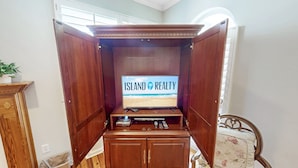 Eine Holz-Multifunktionsmöbel mit einem Flachbildfernseher, der "Island Realty" zeigt.