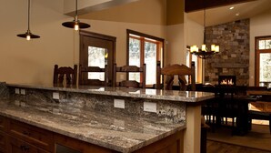 A kitchen with granite countertops, wooden cabinets, and a stone fireplace. - Luxury Home Across from Purgatory with Great Views (Durango)