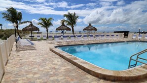 Un área de piscina con sillas de descanso y palmeras.