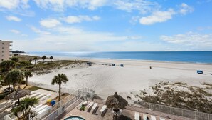 A beach view with a fenced area, lounge chairs, and a pool. - Direct Beachfront - Hot Tub  - Sea Breeze #308 (Madeira Beach)