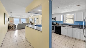 A modern kitchen with white cabinets, a black dishwasher, and a stainless steel refrigerator. - Direct Beachfront - Hot Tub  - Sea Breeze #308 (Madeira Beach)