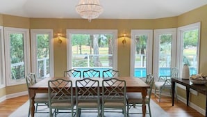 A dining area with a large table, six chairs, and a chandelier.
