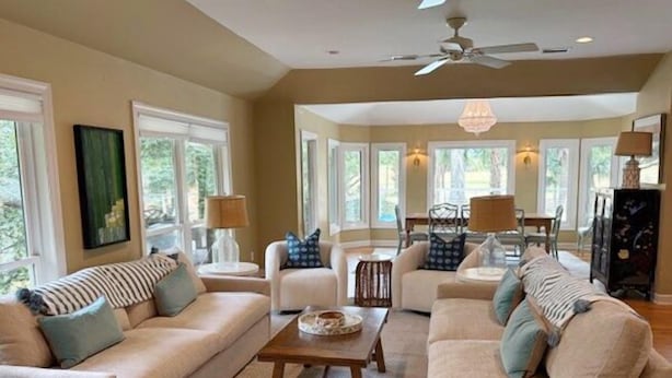 A spacious living room with a beige sofa set, a wooden coffee table, and a chandelier.