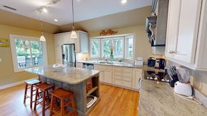 A modern kitchen with a central island, stainless steel appliances, and a large window providing natural light.