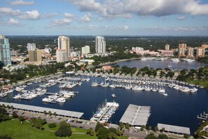 A marina with numerous boats docked, surrounded by buildings and greenery. - Fantastic Beachfront Location. Beachfront Heated Pool. Top Floor Balcony. Spacious and Comfortable. (Madeira Beach)