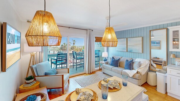 A living room with a sofa, a coffee table, a dining table, and a balcony with outdoor furniture.