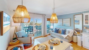 A living room with a sofa, a coffee table, a dining table, and a balcony with outdoor furniture.