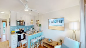 A modern kitchen with white cabinets, a microwave, and a dining area with a table and bar stools.