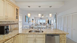 A kitchen with granite countertops, a dishwasher, and a dining area with a table and chairs.