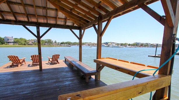 Una terraza de madera con asientos y vista a un puerto deportivo.