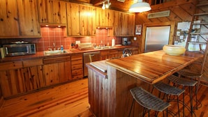 Una cocina de madera con barra, electrodomésticos de acero inoxidable y un refrigerador.