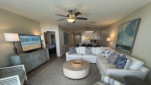 Un salon moderne avec un ensemble de canapés, une table basse et un téléviseur diffusant l'émission « Island Realty ».
