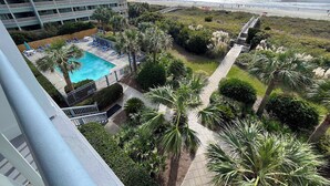 Un hôtel doté d’une piscine, de palmiers et offrant une vue sur la plage.