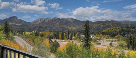 A mountainous landscape with autumn foliage, a road, and a small settlement.