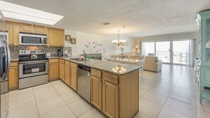 Una cocina amplia con una isla central, electrodomésticos integrados y un amplio comedor con vistas.