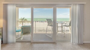 Una habitación con un amplio ventanal corredera que da a un balcón con vistas a la playa.