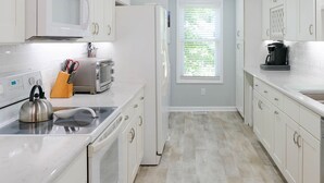 Een moderne keuken met witte kastjes, een magnetron, een broodrooster en een waterkoker.