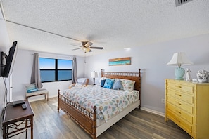 A bedroom with a bed, wooden dresser, and a ceiling fan. - Direct Beachfront - 3b 2b - Beach Place #411 (Madeira Beach)