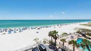 Une plage dotée de nombreux parasols et de chaises longues, une piscine et une vue dégagée sur l’océan.