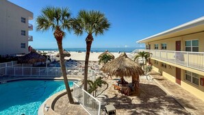 Un complexe hôtelier doté d’une piscine, de palmiers, de parasols de plage et offrant une vue sur l’océan.