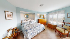 A bedroom with a bed, dresser, chair, and a window with blinds.